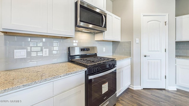 kitchen featuring stainless steel appliances, white cabinetry, light stone counters, tasteful backsplash, and dark hardwood / wood-style floors