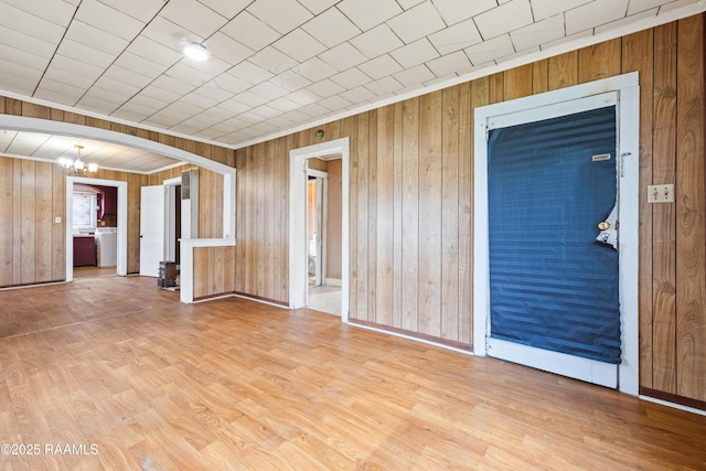 interior space with an inviting chandelier, hardwood / wood-style flooring, washer / dryer, and wood walls