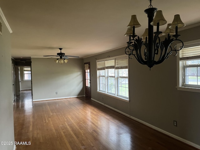 unfurnished room with dark wood-type flooring, a wealth of natural light, crown molding, and ceiling fan with notable chandelier