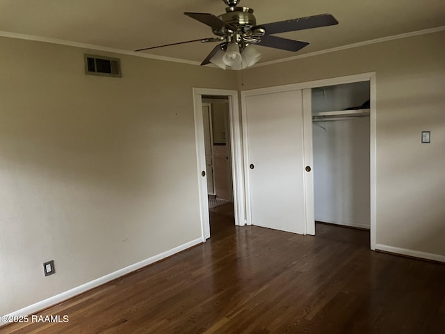 unfurnished bedroom featuring ceiling fan, a closet, dark wood-type flooring, and crown molding