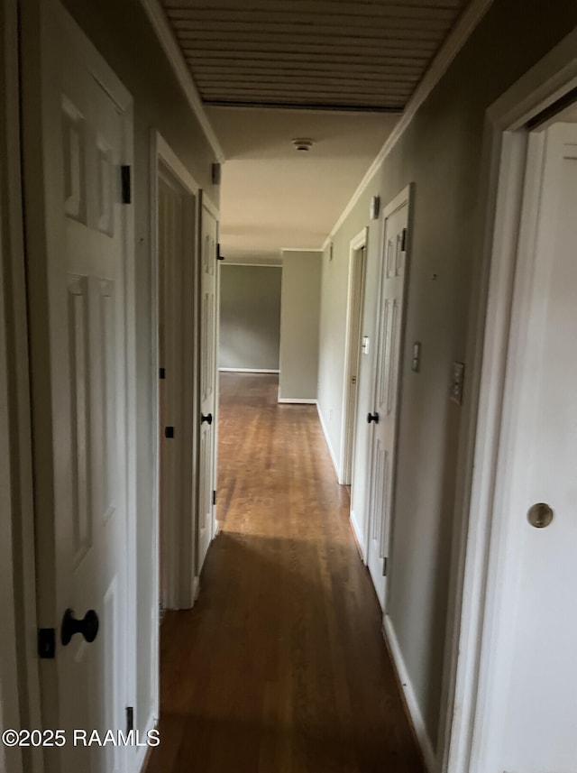 corridor with dark wood-type flooring and crown molding