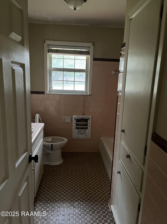 bathroom with vanity, tile walls, toilet, a bath, and heating unit