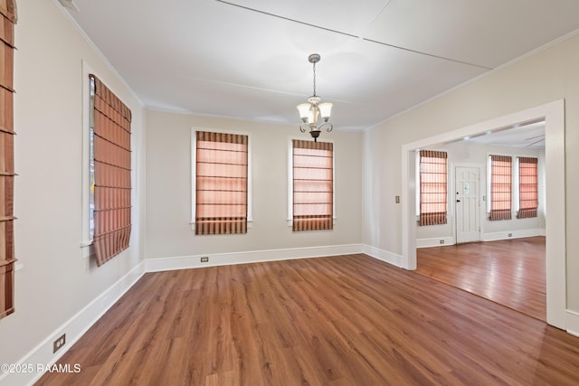 spare room featuring a chandelier, crown molding, and wood-type flooring