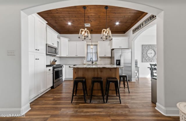 kitchen featuring wood ceiling, stainless steel appliances, a center island, pendant lighting, and white cabinetry