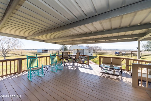 wooden terrace featuring a yard, a rural view, and a storage shed