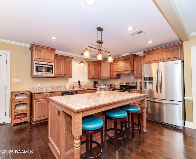 kitchen with stainless steel appliances, custom exhaust hood, a center island, and crown molding