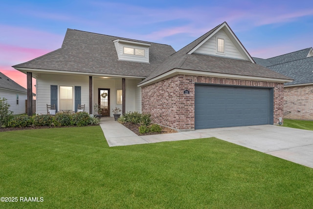 view of front of home with a yard, covered porch, and a garage