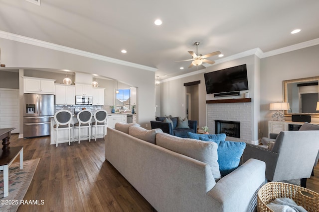 living room featuring ceiling fan, dark hardwood / wood-style flooring, ornamental molding, and a fireplace