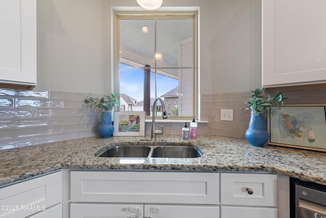 kitchen featuring sink, white cabinetry, and light stone countertops