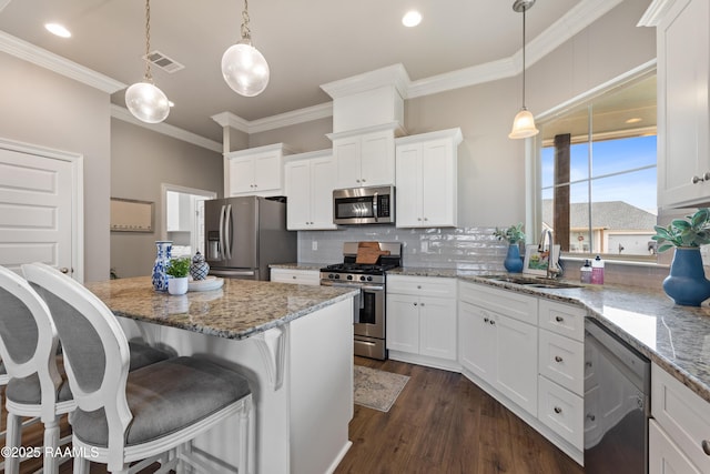 kitchen with decorative light fixtures, stainless steel appliances, white cabinets, and sink