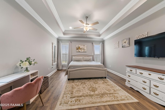 bedroom with dark hardwood / wood-style flooring, ceiling fan, a tray ceiling, and ornamental molding