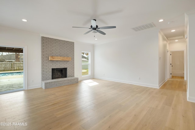 unfurnished living room featuring light hardwood / wood-style flooring, a brick fireplace, and plenty of natural light