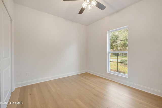 empty room with ceiling fan, a wealth of natural light, and light wood-type flooring