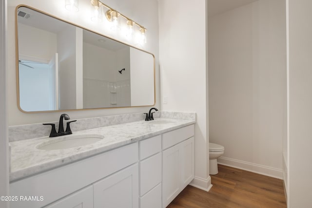 bathroom with hardwood / wood-style flooring, vanity, a shower, and toilet