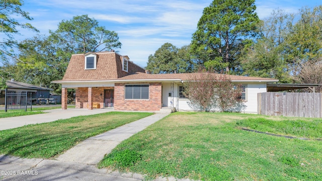 view of front of house with mansard roof, roof with shingles, fence, a front lawn, and brick siding