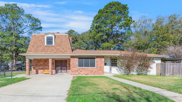 view of front of house featuring a shingled roof, a front yard, brick siding, and fence