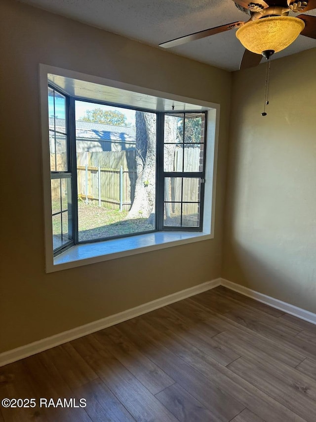 empty room with a textured ceiling, a healthy amount of sunlight, and hardwood / wood-style flooring