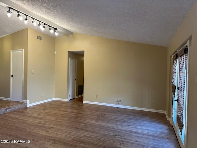 spare room with wood-type flooring, a textured ceiling, and lofted ceiling