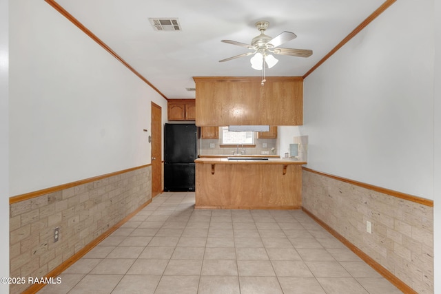 kitchen featuring a kitchen bar, black refrigerator, kitchen peninsula, ceiling fan, and crown molding