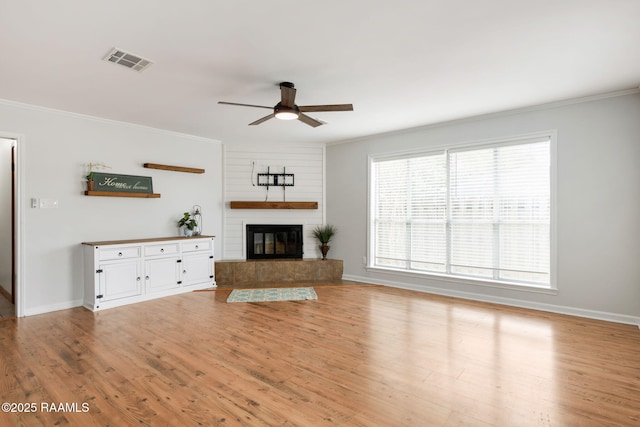 unfurnished living room with ceiling fan, light hardwood / wood-style flooring, ornamental molding, and a fireplace