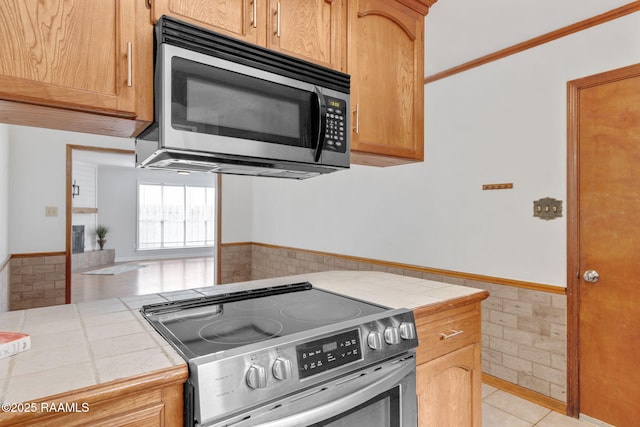 kitchen with light tile patterned floors, appliances with stainless steel finishes, and tile countertops