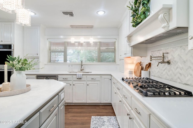 kitchen featuring a notable chandelier, custom exhaust hood, pendant lighting, and white cabinetry