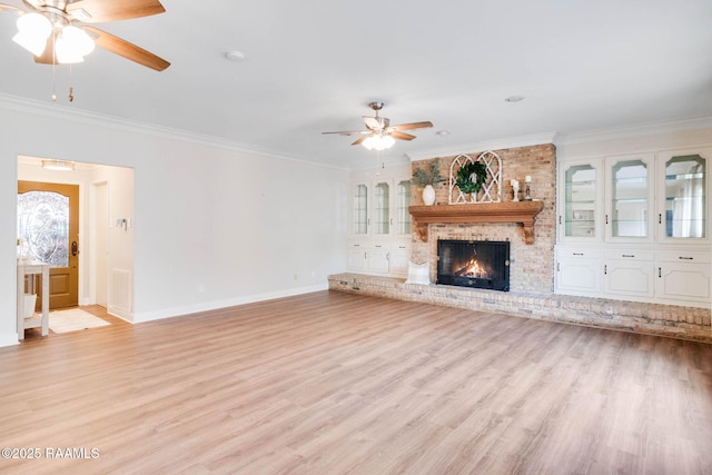 unfurnished living room with a brick fireplace, ornamental molding, ceiling fan, and light hardwood / wood-style flooring