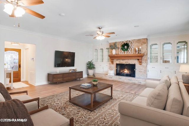 living room with ceiling fan, light hardwood / wood-style flooring, crown molding, and a fireplace