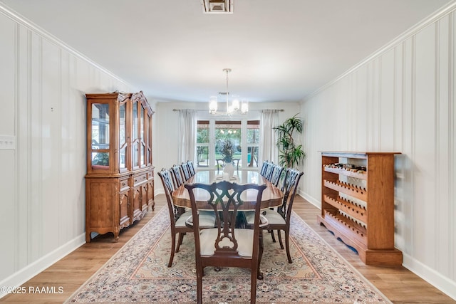 dining area with a notable chandelier, crown molding, and light hardwood / wood-style flooring