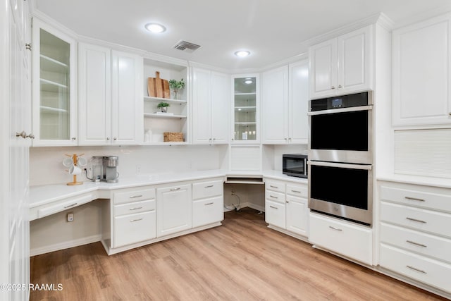 kitchen featuring built in desk, white cabinetry, light hardwood / wood-style floors, double oven, and built in microwave