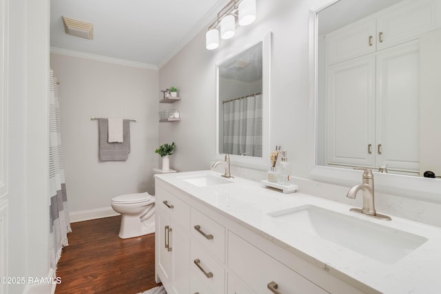 bathroom with ornamental molding, toilet, vanity, and wood-type flooring