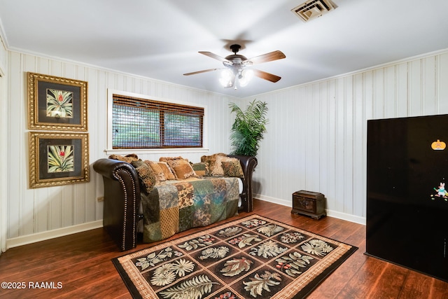 living room featuring ceiling fan, ornamental molding, and dark wood-type flooring