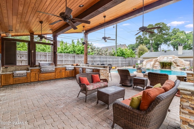 view of patio featuring an outdoor hangout area, a grill, ceiling fan, a fenced in pool, and exterior kitchen