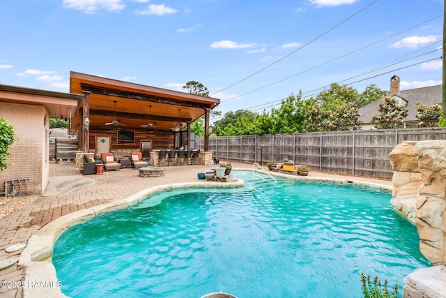 view of swimming pool featuring ceiling fan, an outdoor bar, and a patio