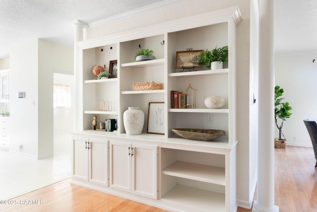 interior space with a textured ceiling, ornamental molding, built in features, and hardwood / wood-style flooring