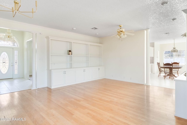 unfurnished living room with ceiling fan, a textured ceiling, built in shelves, and light wood-type flooring