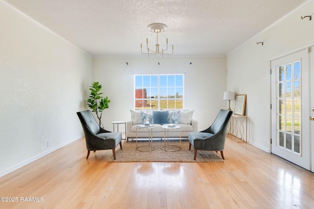 sitting room with hardwood / wood-style flooring, crown molding, a chandelier, and a textured ceiling