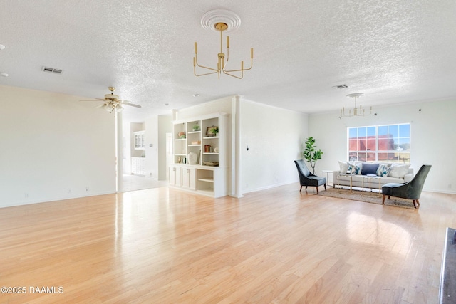 living room with a textured ceiling, ceiling fan with notable chandelier, light hardwood / wood-style flooring, and built in shelves