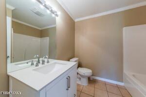 bathroom featuring toilet, vanity, tile patterned flooring, and ornamental molding