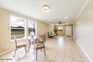 tiled dining space featuring ceiling fan and ornamental molding