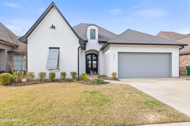 french provincial home featuring a garage, a front yard, and french doors