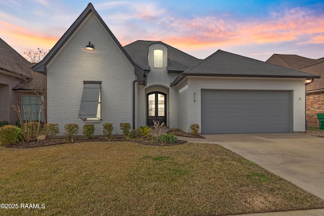 french country inspired facade featuring a garage and a lawn