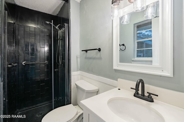 bathroom with tiled shower, vanity, toilet, and a textured ceiling