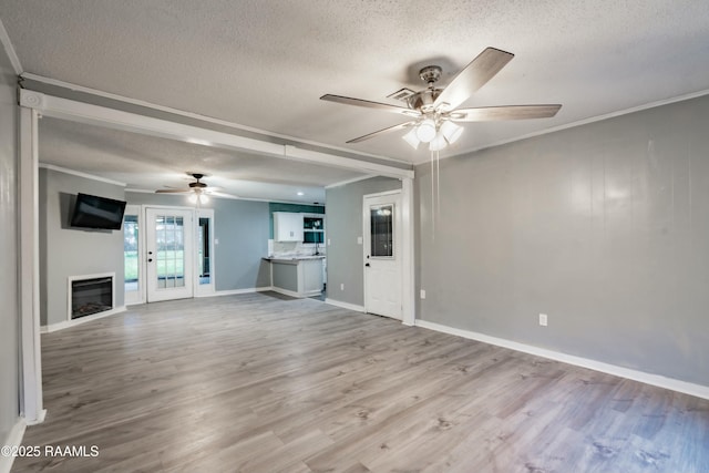 unfurnished living room featuring ceiling fan, crown molding, light hardwood / wood-style floors, and a textured ceiling