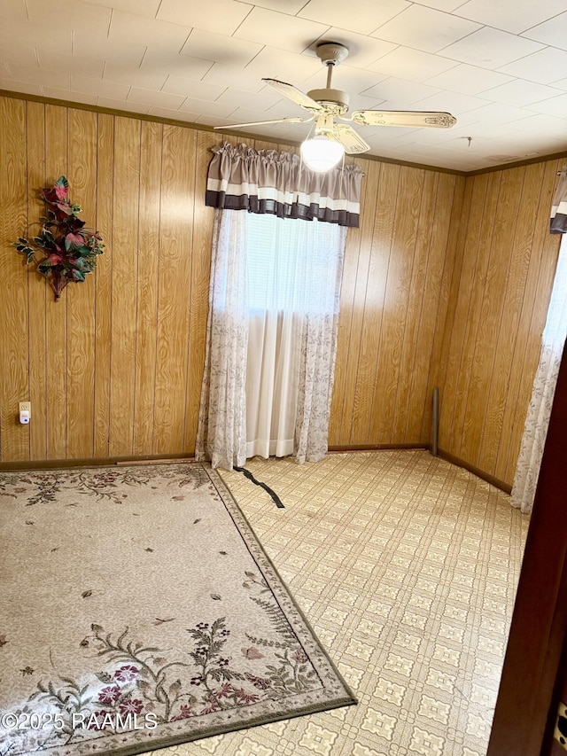 unfurnished room with ceiling fan and wooden walls