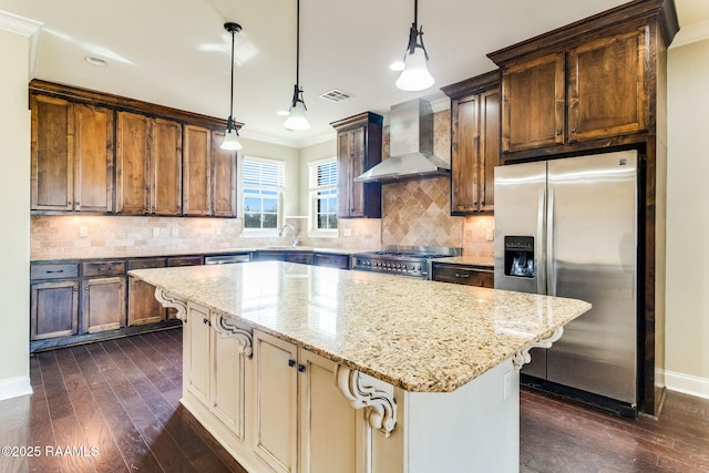 kitchen with light stone counters, stainless steel appliances, a center island, and wall chimney exhaust hood