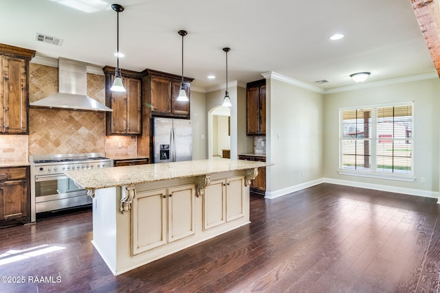 kitchen featuring a kitchen breakfast bar, stainless steel appliances, a center island, and wall chimney exhaust hood