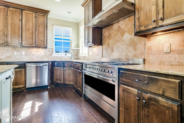 kitchen featuring appliances with stainless steel finishes, backsplash, ornamental molding, light stone counters, and wall chimney range hood