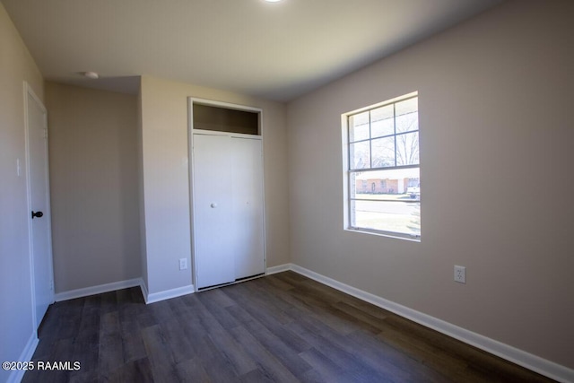 unfurnished bedroom with a closet and dark wood-type flooring