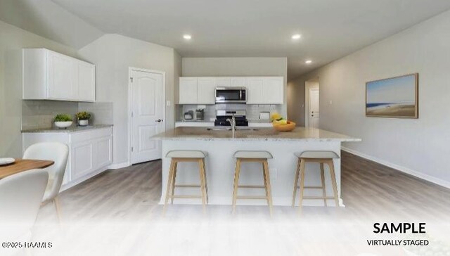 kitchen featuring tasteful backsplash, a kitchen island with sink, appliances with stainless steel finishes, and white cabinetry